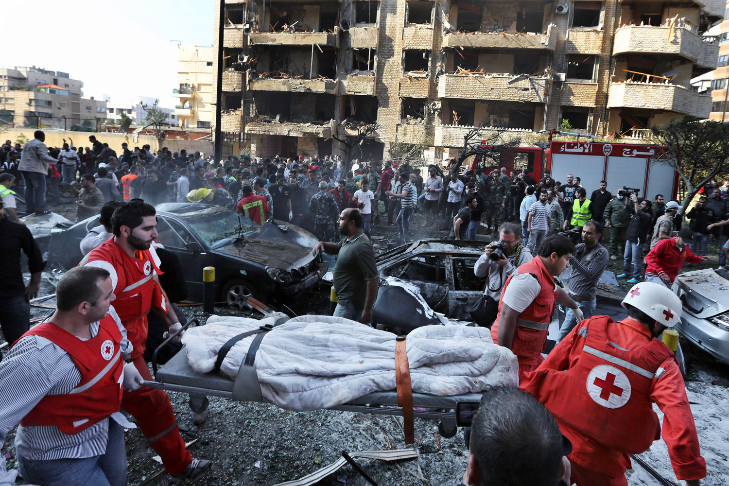 Nov. 19, 2013. Lebanese Red Cross workers, carry a dead body at the scene where two explosions have struck near the Iranian Embassy killing many, in Beirut, Lebanon.