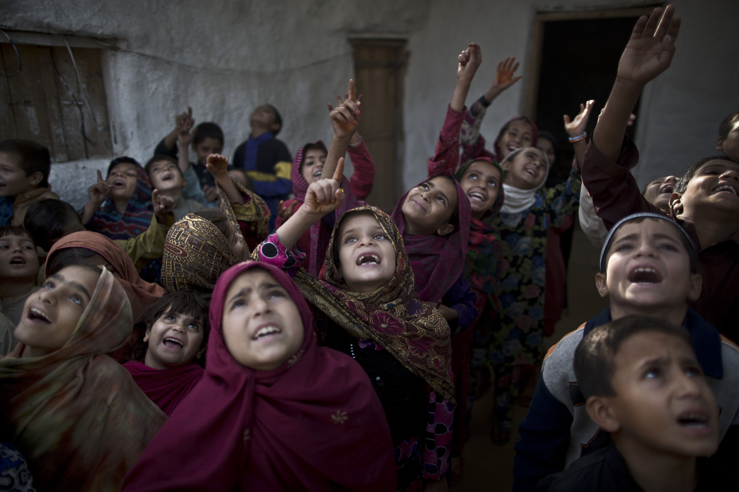 Oct. 31, 2013. Afghan refugees, and Pakistani school children, who were displaced with their families from Pakistan's tribal areas due to fighting between the Taliban and the army, sing with their teacher during the morning assembly, before starting their classes, at their makeshift school on the outskirts of Islamabad, Pakistan.