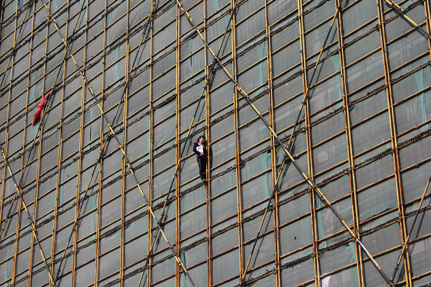A woman holds a portrait of her husband as she threatens to jump off a scaffolding at a construction site in Wenzhou