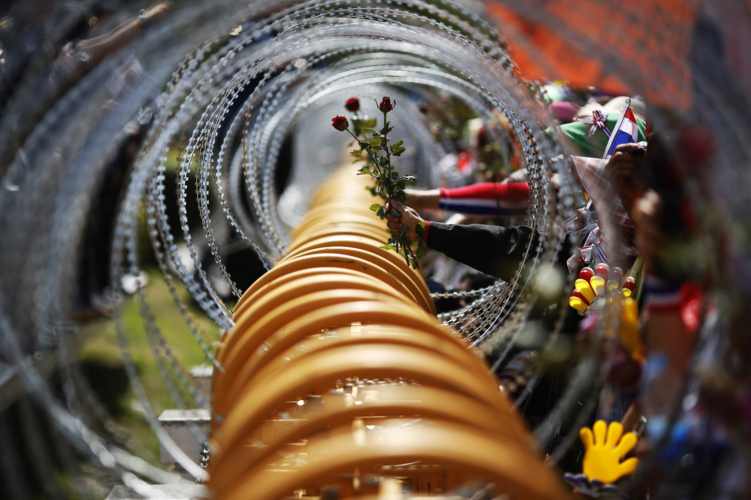 Anti-government protesters give roses, through razor wire, to the security personnel guarding the Defense Ministry in Bangkok