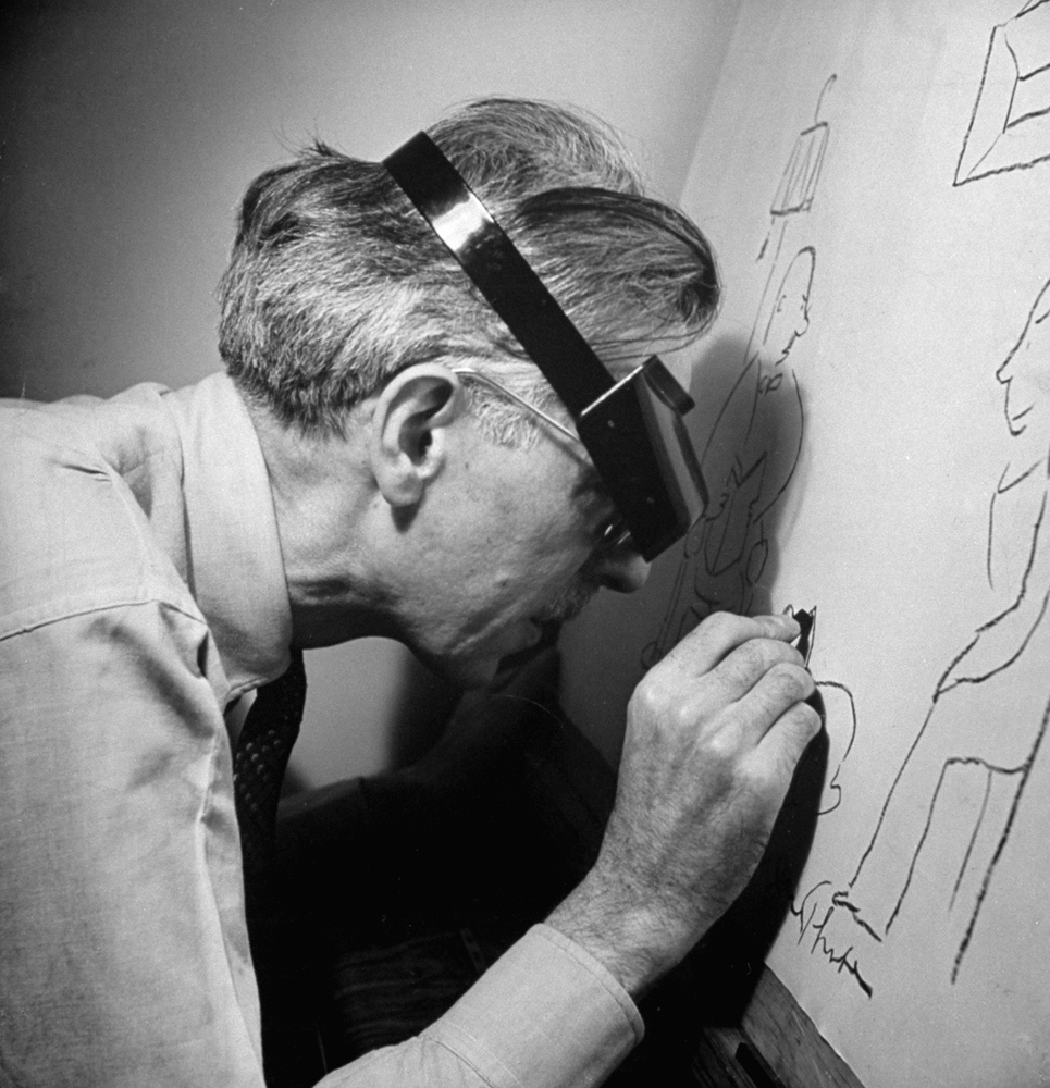 James Thurber draws with a tremulous hand on large sheets of yellow paper. Powerful watchmaker's magnifier helps his good eye to see what he is doing.
