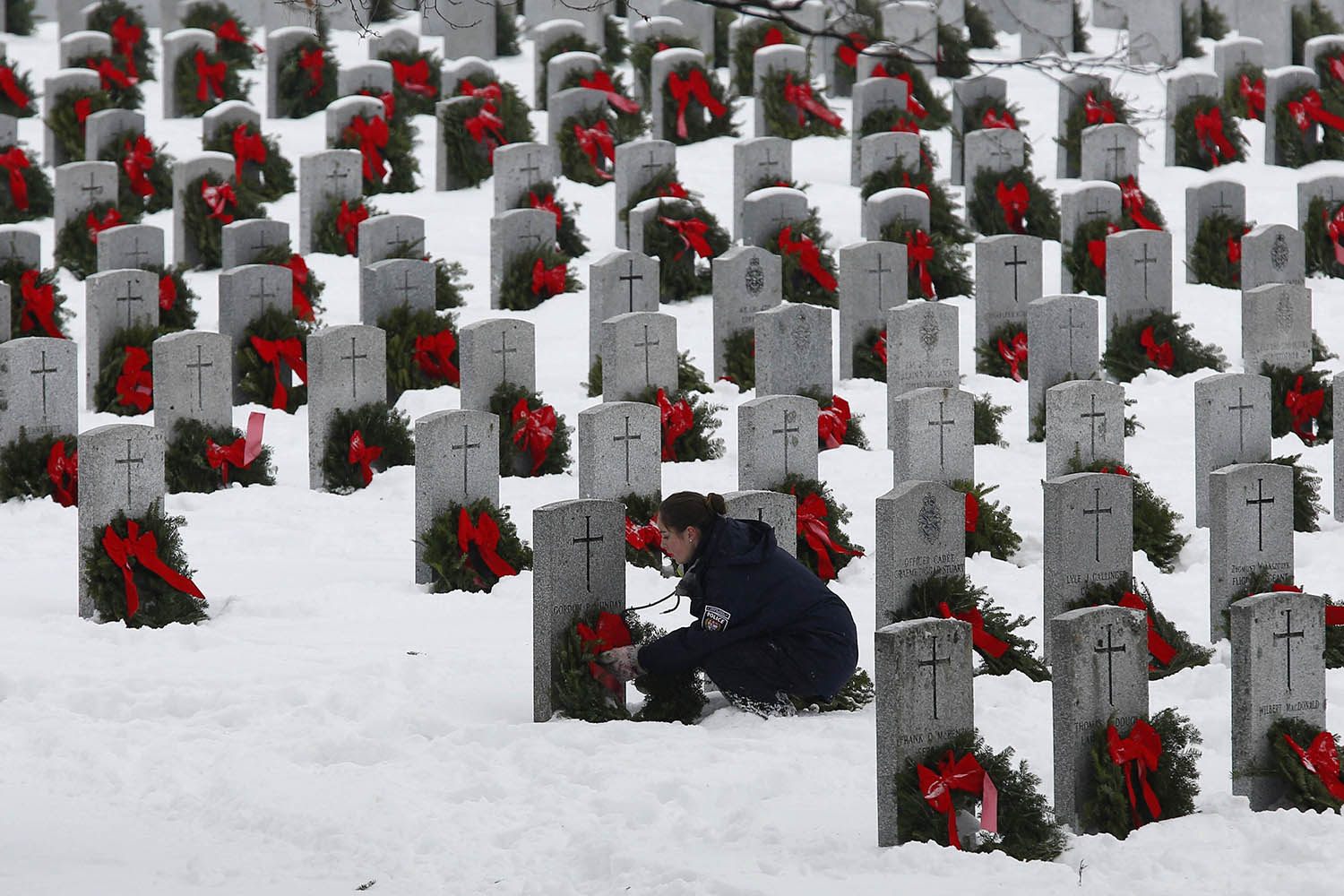 A woman adjusts a wreath during the Wreaths Across Canada ceremony at the National Military Cemetery in Ottawa
