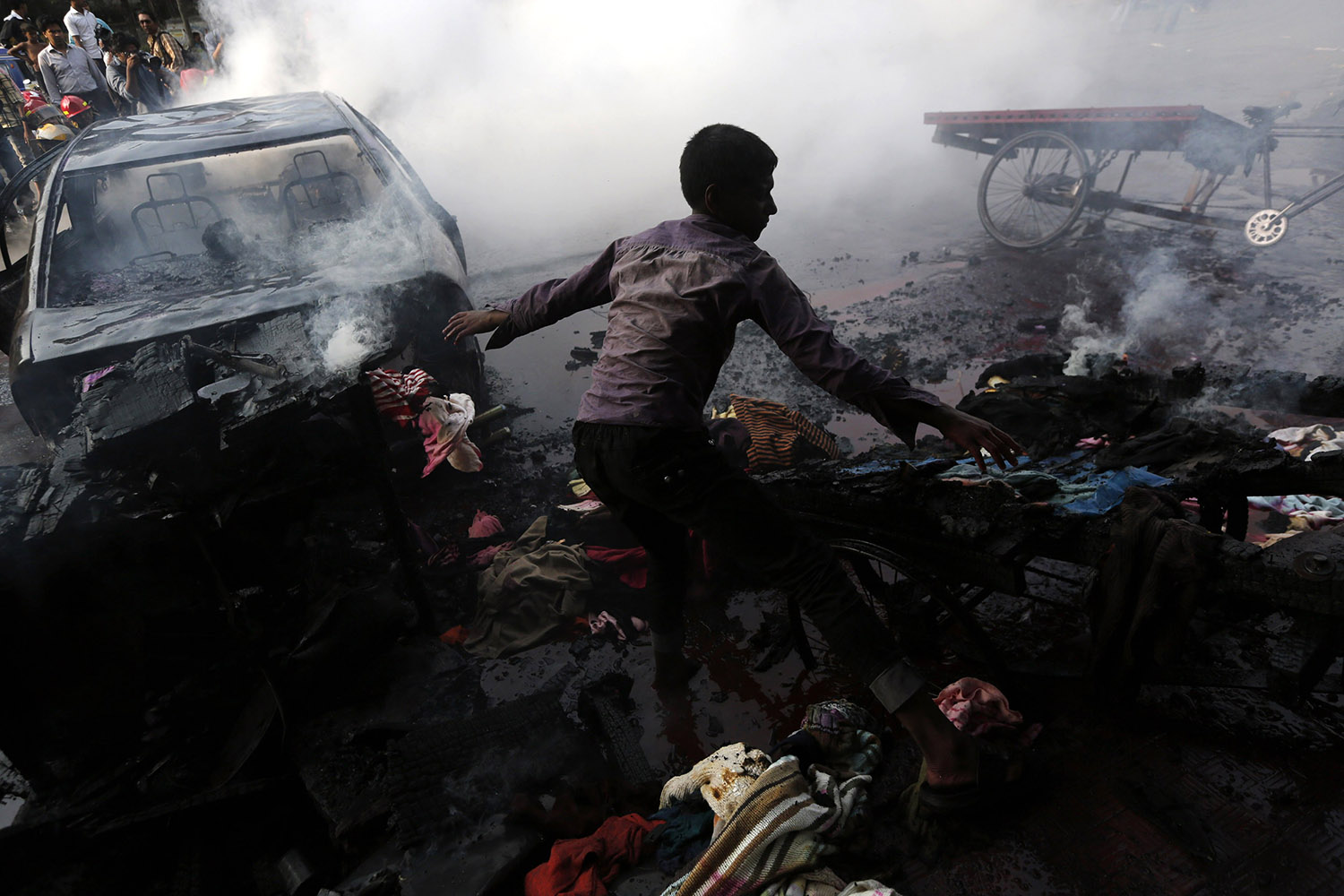 A boy tries to control a fire after vehicles were torched and vandalized by Bangladesh's Jamaat-e-Islami party activists during clashes with police in Dhaka