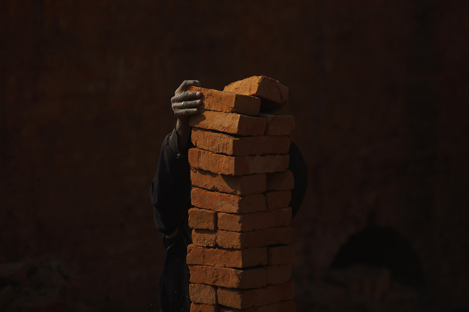 A man stack bricks before carrying them at a brick factory in Lalitpur