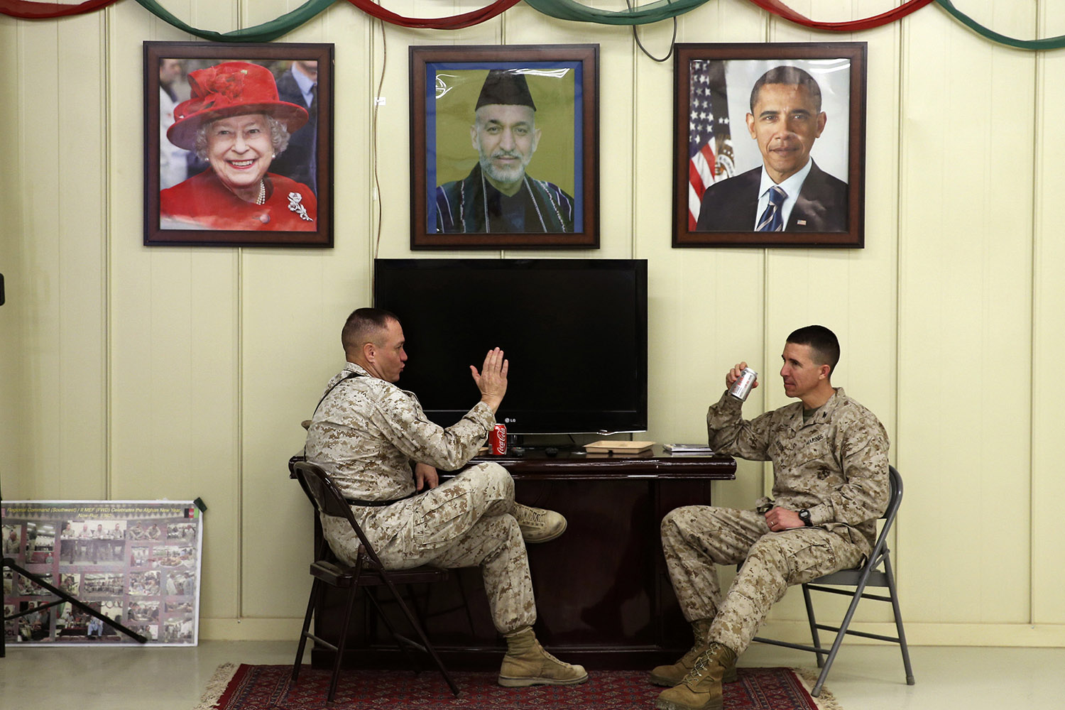 U.S. Marines Lt. Col. Clint Benfield and Col. Ben Watson talk under pictures of Queen Elizabeth, Afghan President Karzai and U.S. President Obama at Camp Bastion