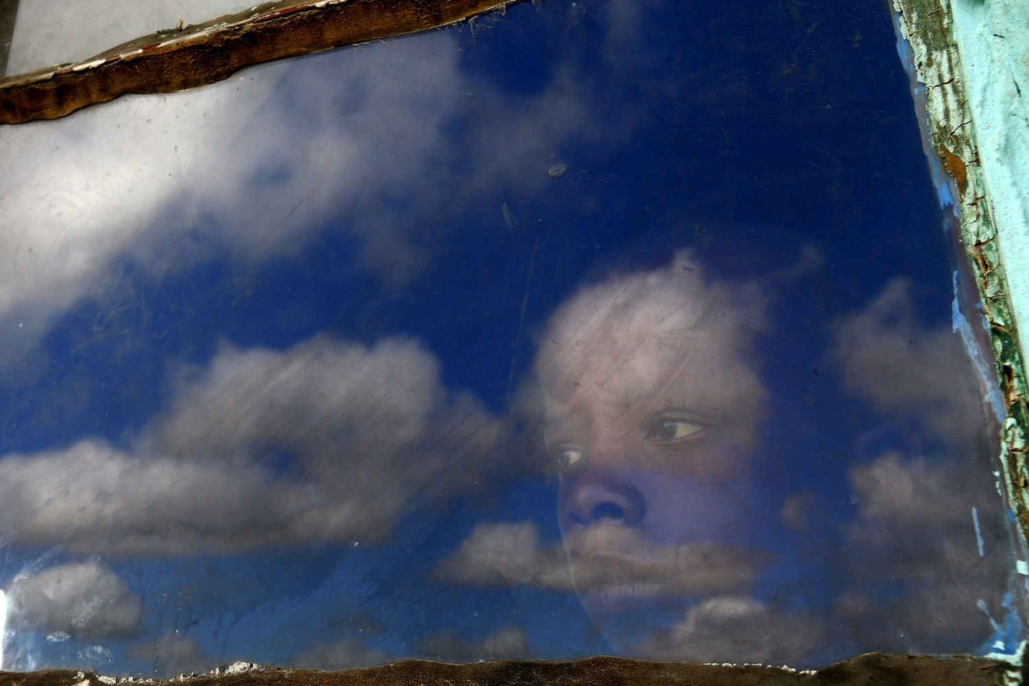A local boy, Anda, looks out from his hut's window at the burial ground of late former South African President Nelson Mandela ahead of his funeral in Qunu