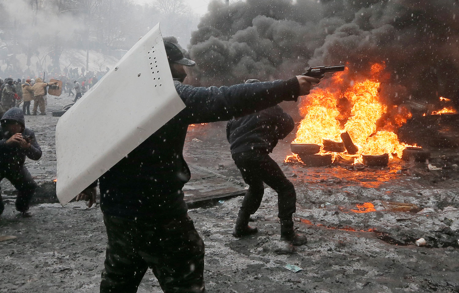 A protester points a handgun during a clash with police in central Kiev,  Jan. 22, 2014.