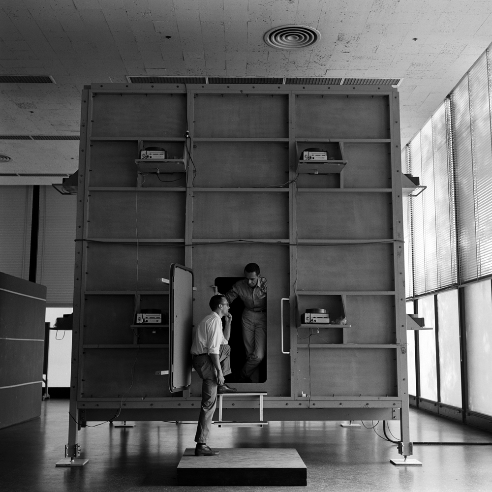Designer Ken Isaacs confers with a colleague while standing in doorway of his "knowledge box," 1962.