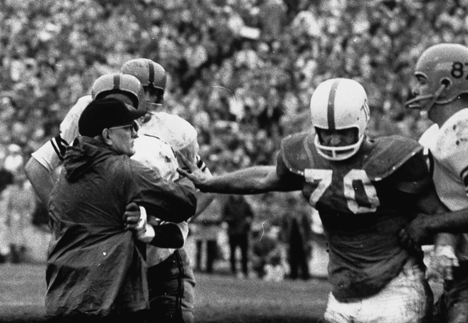Syracuse coach Benny Schwartzwalder on the field during the 1960 Cotton Bowl against Texas, trying to break up a fight.