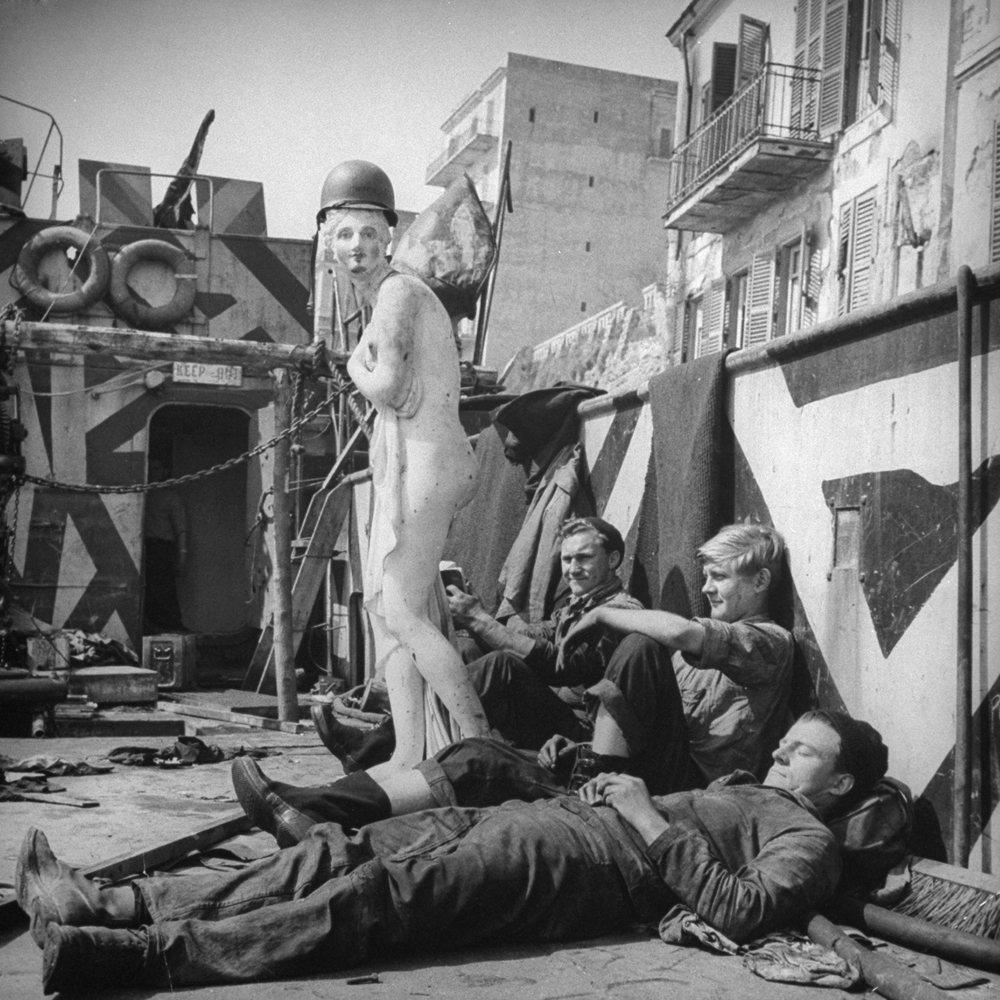 American soldiers relax with their mascot, "Axis Sally," which was "liberated" during the battle for control of the Anzio beachhead, 1944.