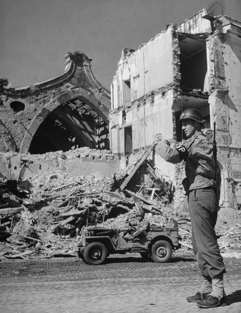 American Military Policeman Ray E. Kellogg directs traffic in bomb-shattered Anzio, 1944.