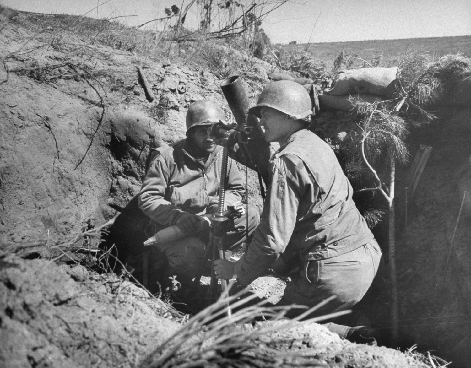 American soldiers sight a mortar from a dugout behind road embankment during the fight for Anzio, 1944.