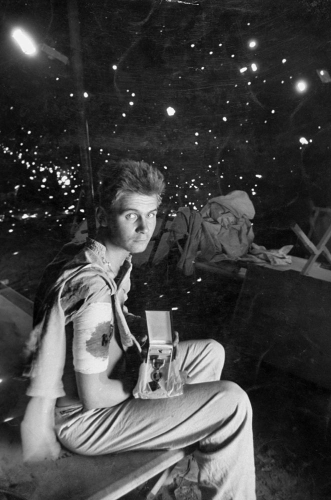 Private Robert Scullion holds the Purple Heart he was awarded after being wounded by shellfire while in the hospital, Anzio. (Note shrapnel holes in tent wall.)