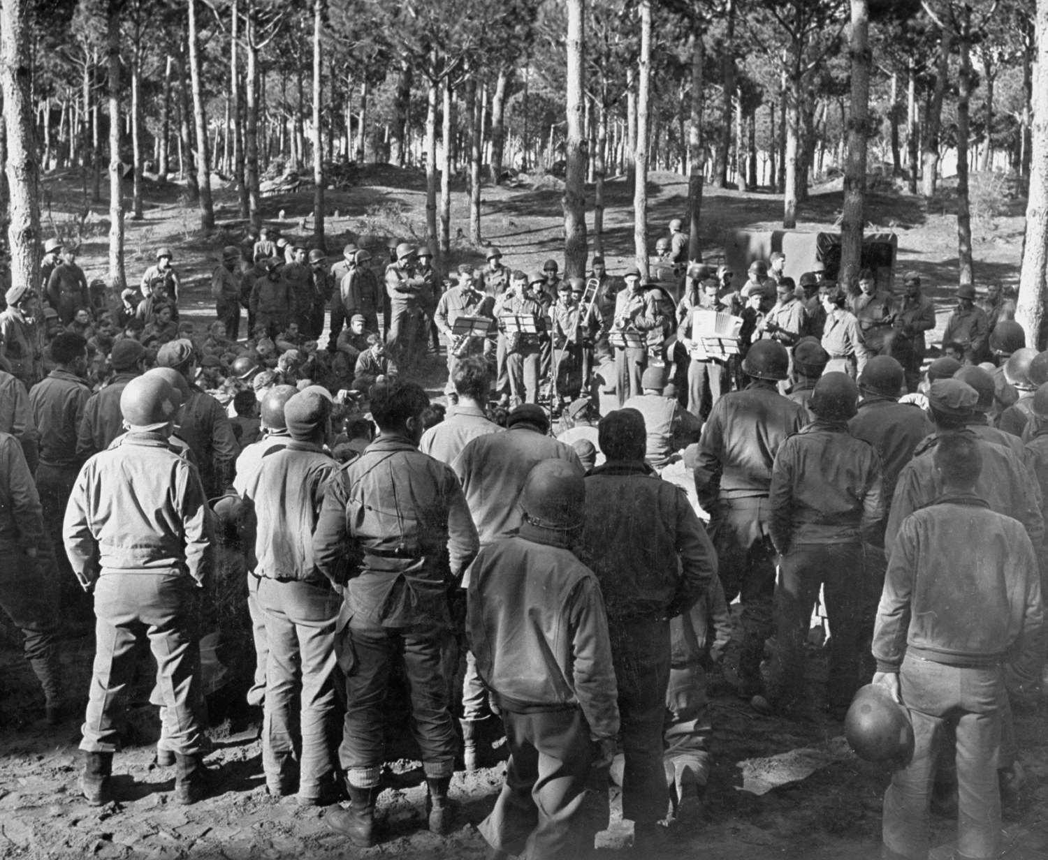 At a rest camp only 2,000 yards from the front veterans are entertained by a band. Located in woods, camp is one of few places on the beachhead even partly screened from German observation. Men are generally sent for 48 hours of relief from the ceaseless shelling.