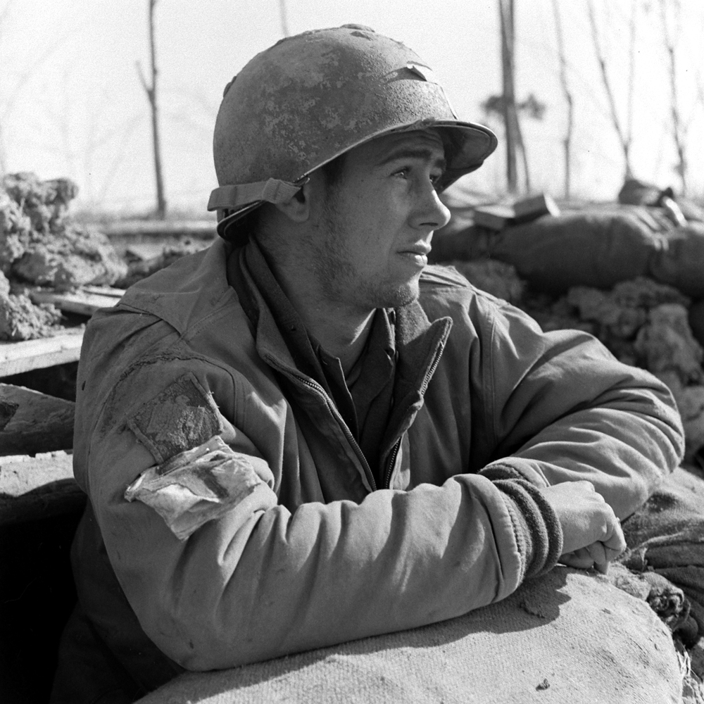 Medic, Pvt. E. Armitage, Mass., laps up some sunshine at the mouth of his foxhole, Anzio, 1944.