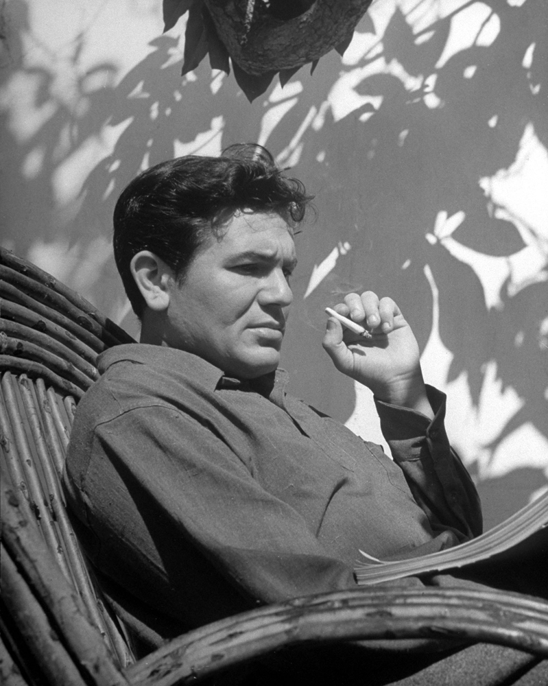 Actor John Garfield smokes and studies the script for the movie, 'They Made Me a Criminal.'