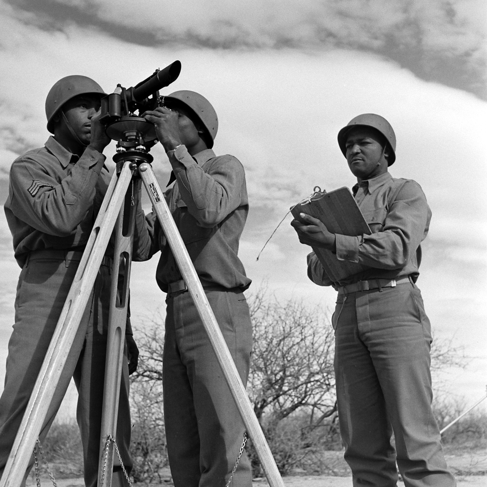 During infantry artillery practice at Fort Huachuca, Pfc. Alphonso Cohen and Cpl. Leslie Anderson line up target for their guns with careful use of an aiming circle.