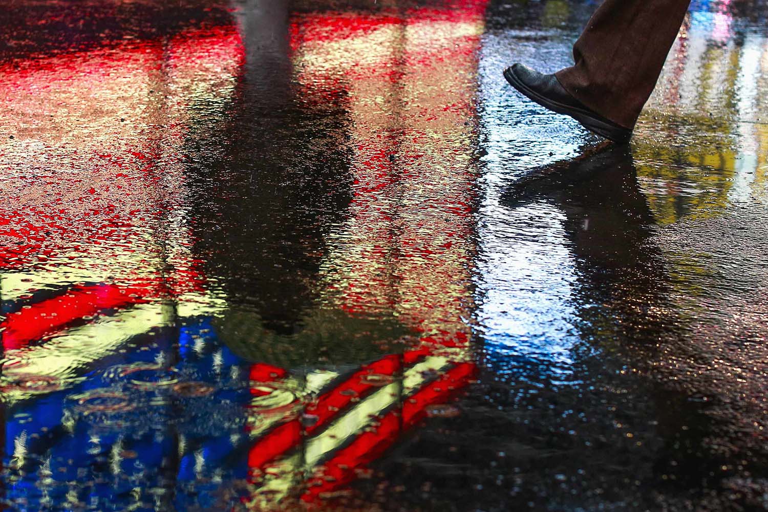 People walk through puddles during a morning snow mixed with rain shower at Times Square located in the Manhattan borough of New York