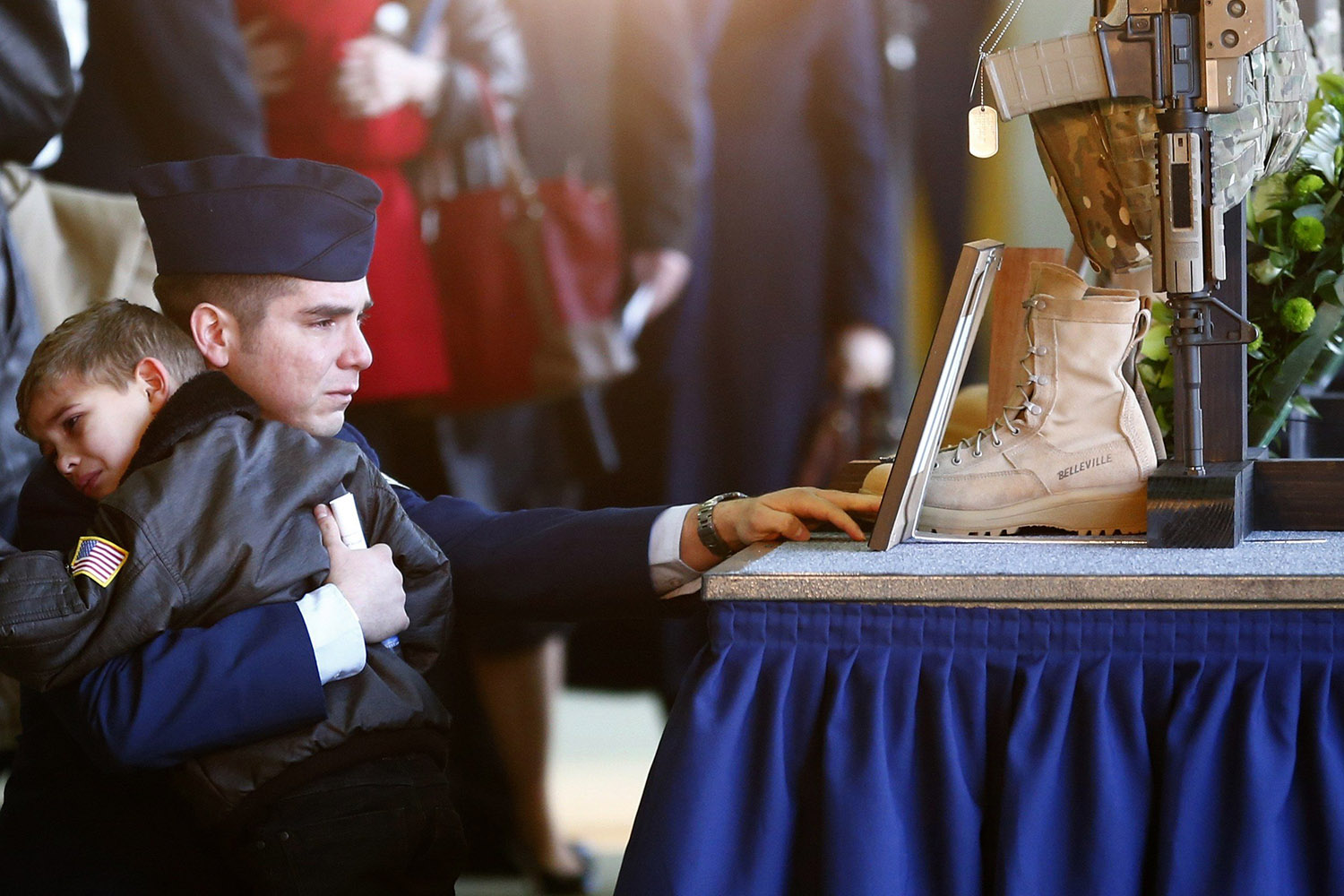 Jan. 17, 2014. A man and a boy kneel in front of the weapon, equipment and uniform of Staff Sgt Afton Ponce who died in a helicopter accident, after a memorial service at RAF Lakenheath in eastern England.