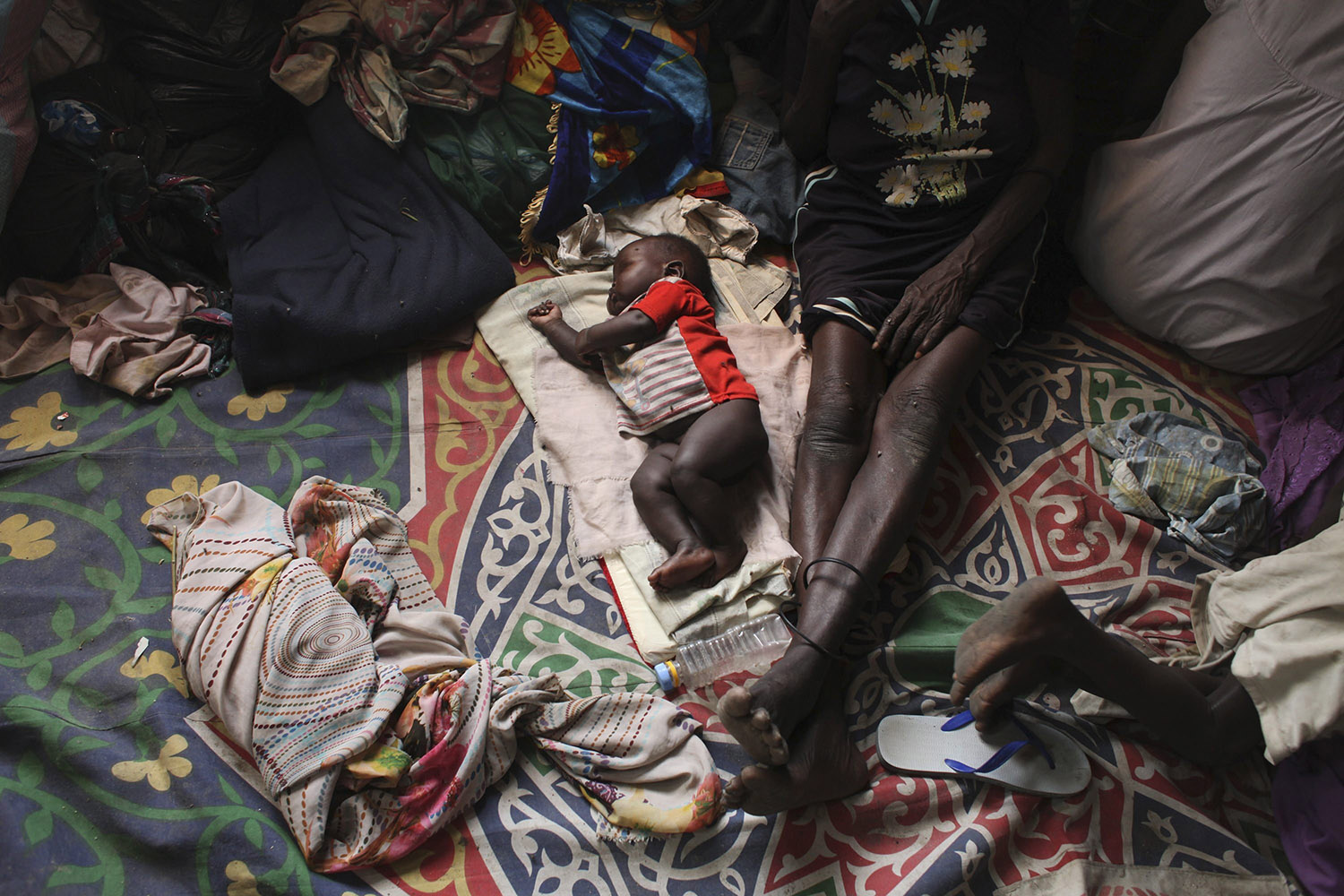 A baby sleeps next to a woman in a Catholic church in Malakal
