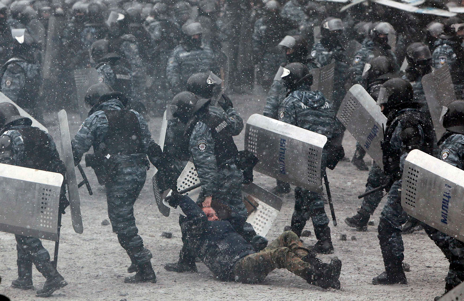 Riot police officers hold a man during clashes with pro-European protesters in Kiev, Jan. 22, 2014.