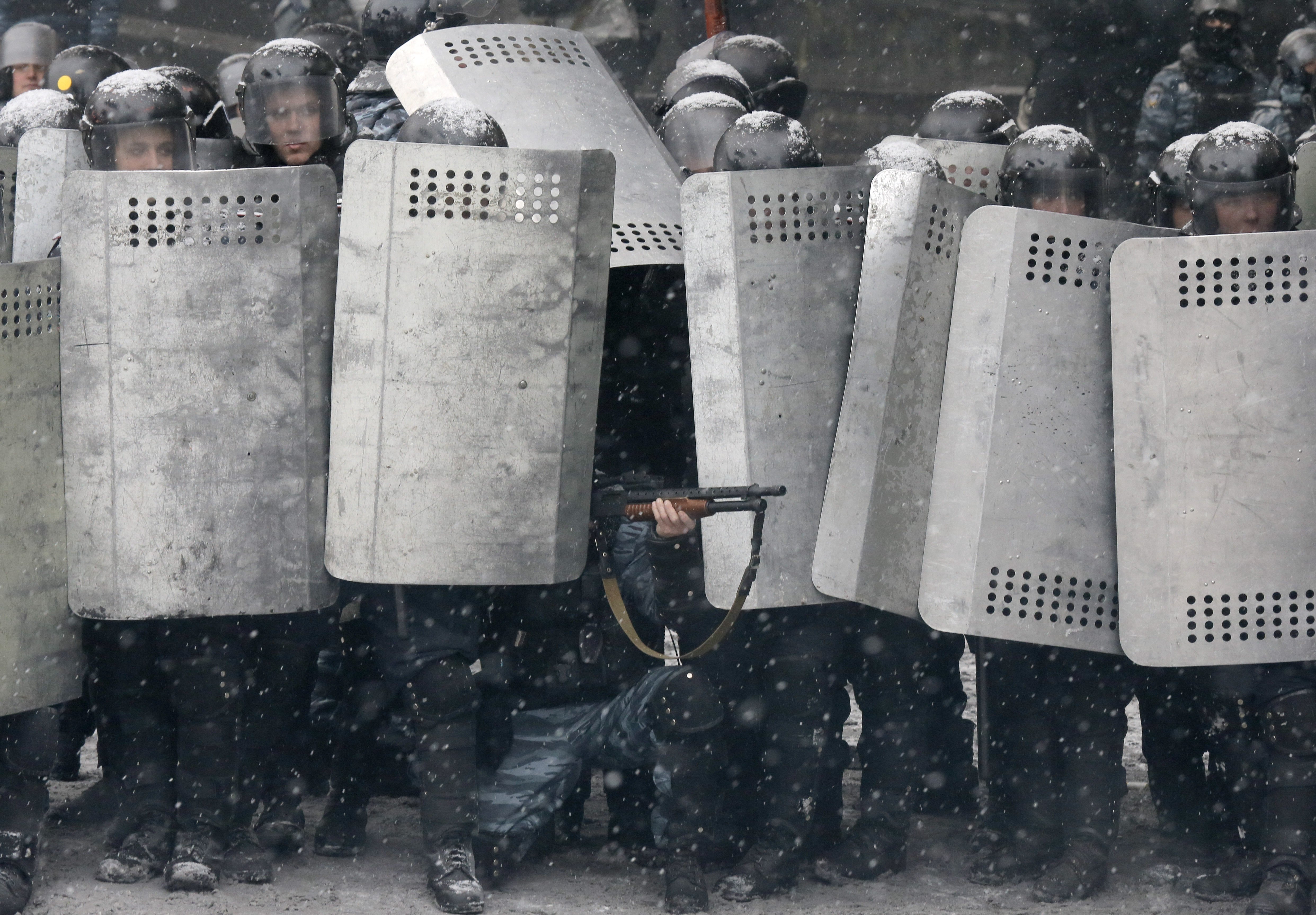 A police officer aims his shotgun during clashes with protesters in central Kiev, Jan. 22, 2014.