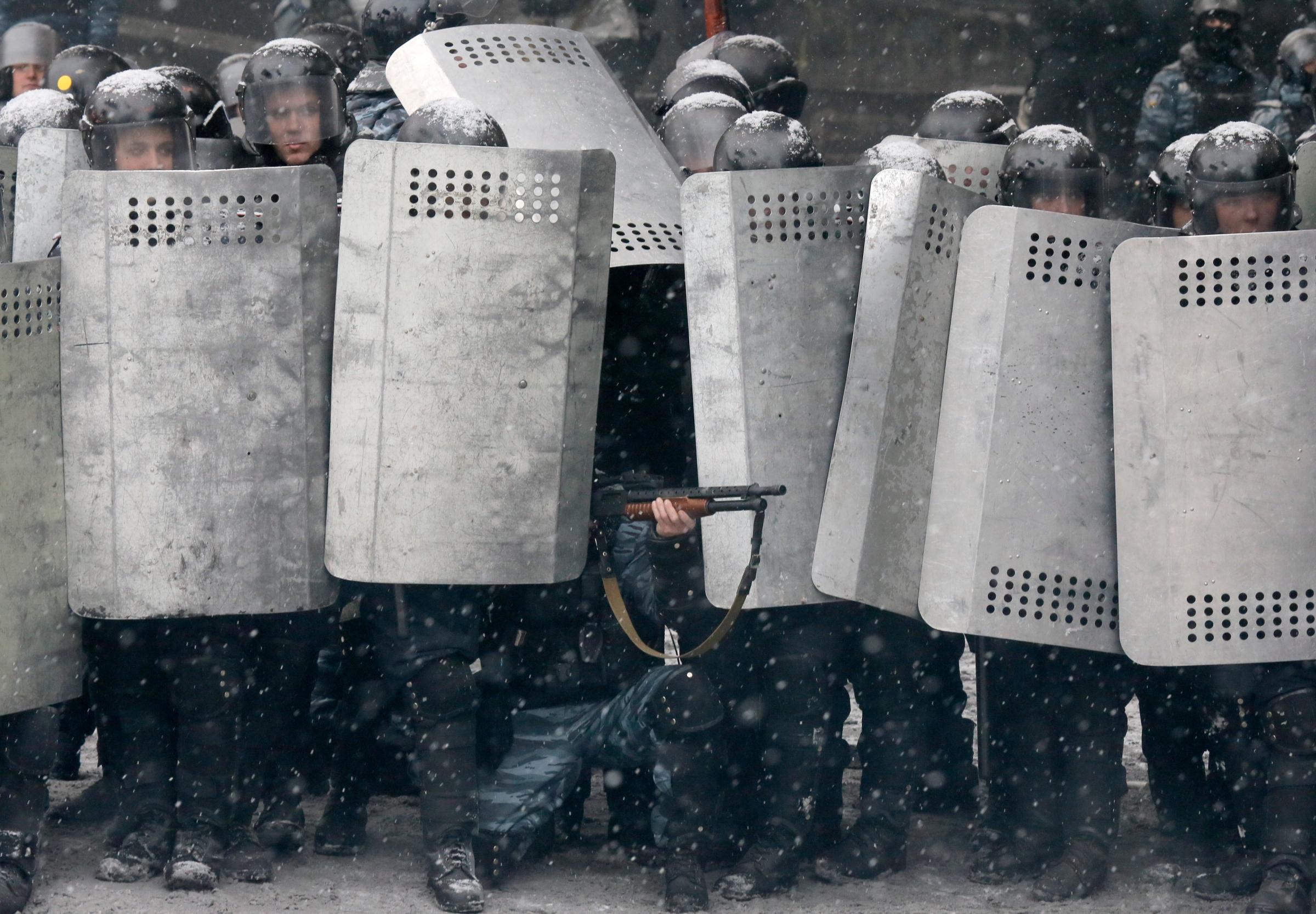 A police officer aims his shotgun during clashes with protesters in central Kiev, Jan. 22, 2014.
