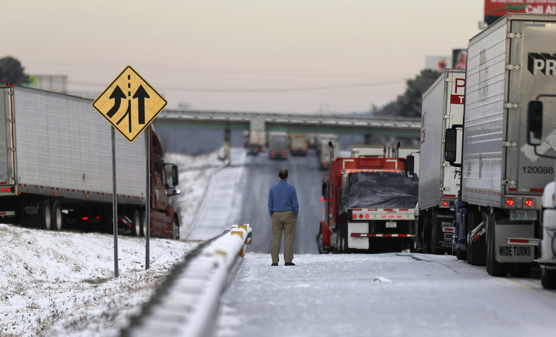 A man stands on the frozen roadway as he waits for traffic to clear along Interstate 75 Wednesday, Jan. 29, 2014, in Macon, Ga.