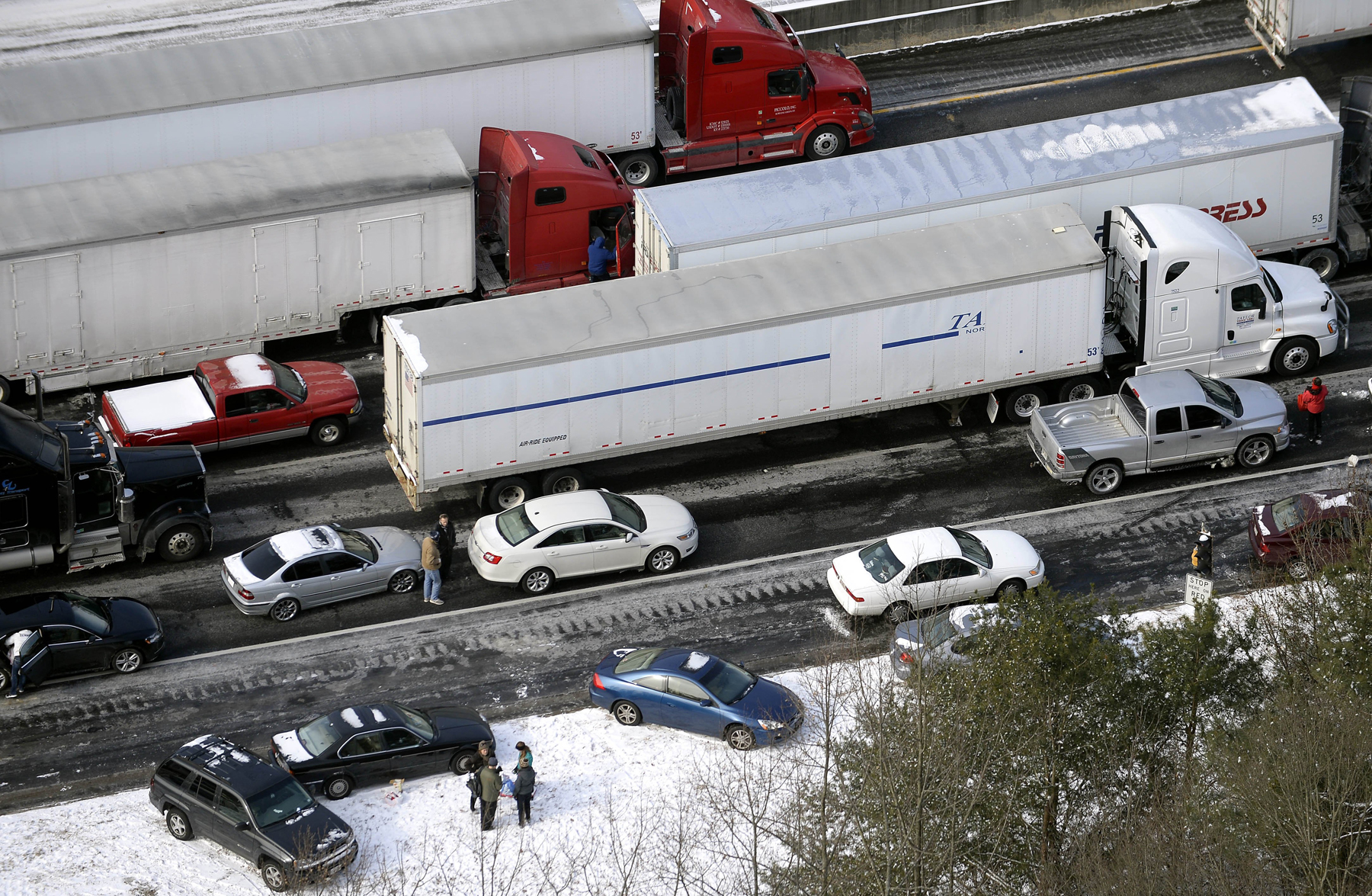 Motorists get out of their vehicles to chat near abandoned cars along the ice-covered I-75 north at Moors Mill Rd., Jan. 29, 2014, in Atlanta.