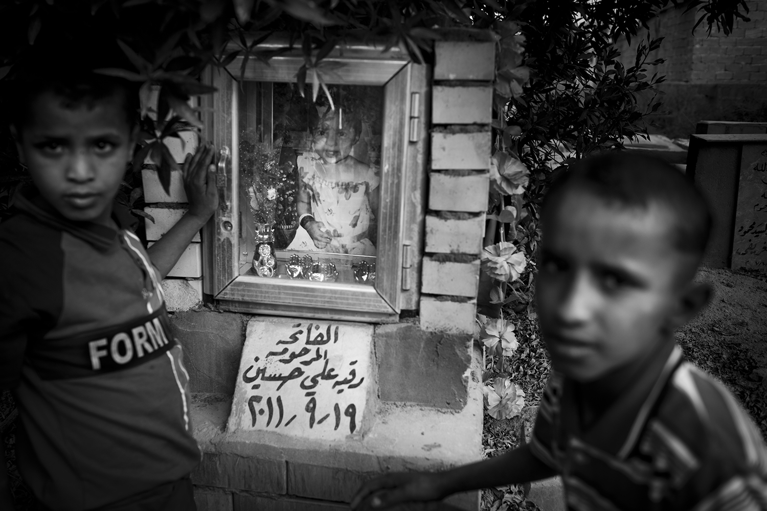 Apr. 21, 2012. Basra. Two boys by the grave of a young girl in the children's cemetery.