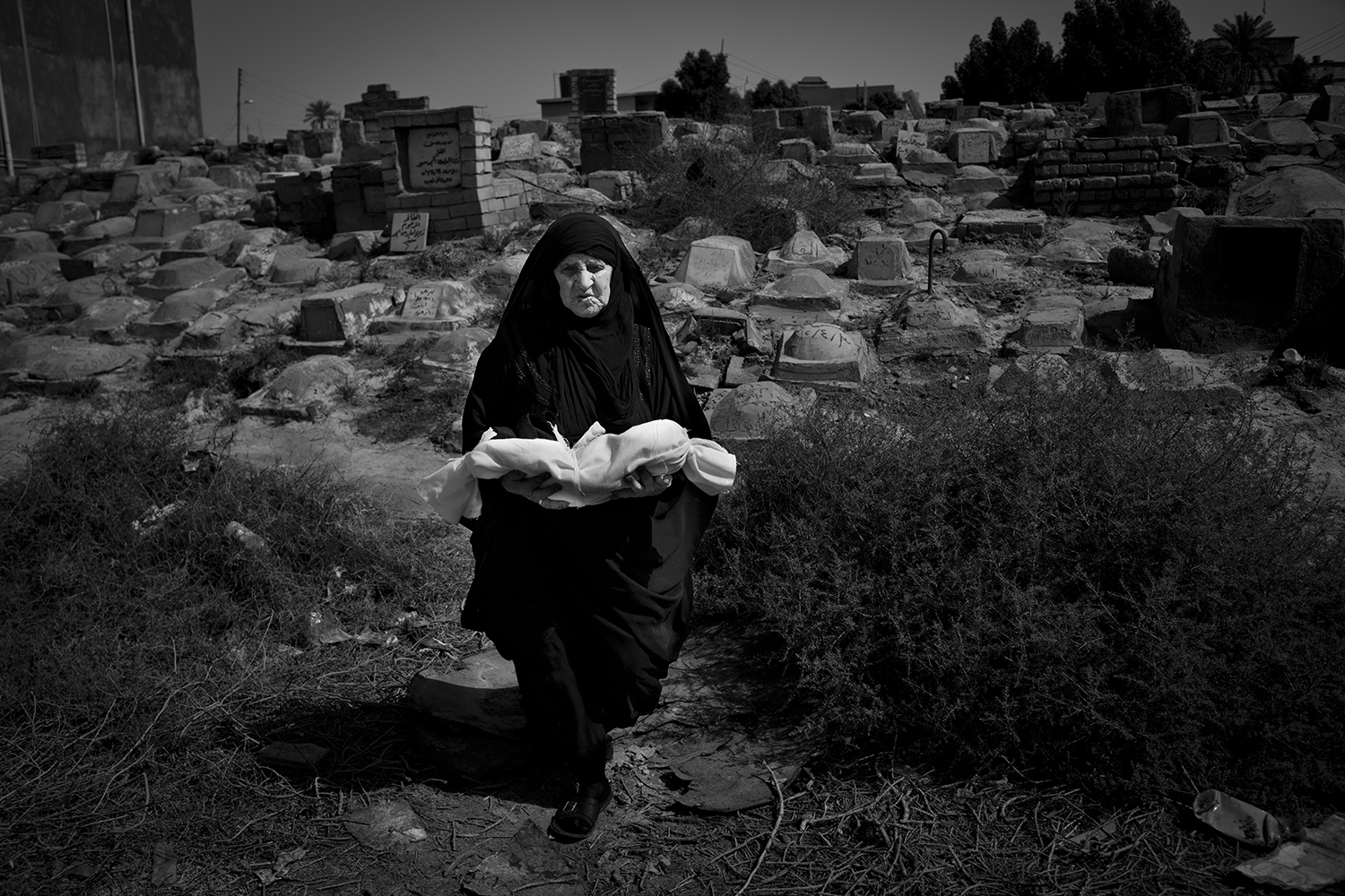 Apr. 24, 2012. Basra. An elderly woman carries the linen-wrapped body of a stillborn baby at the children’s cemetery.