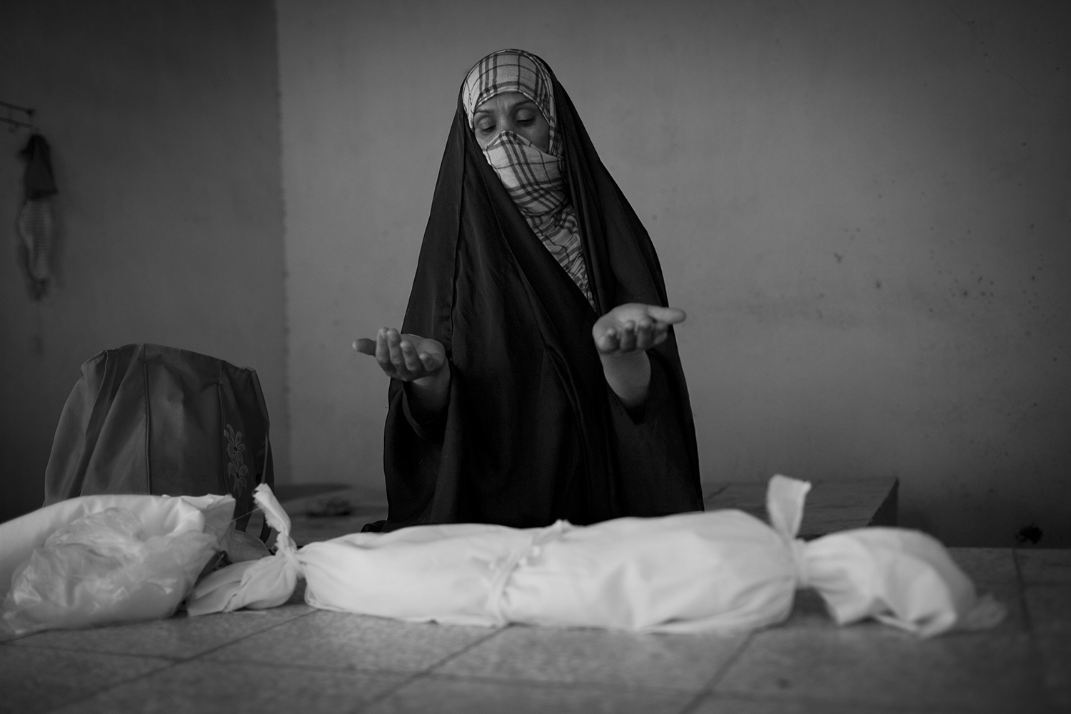 Oct. 22, 2012. Basra. An undertaker prays for a stillborn boy who is wrapped in linen cloth before his burial at the children's cemetery.