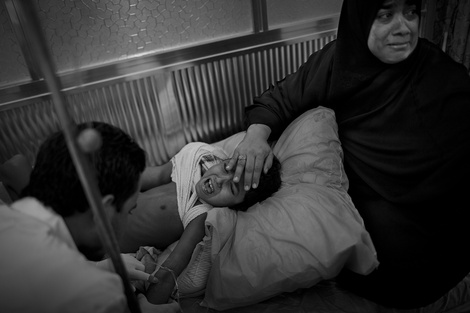 Oct. 24, 2012. Near Basra. A 10-year-old boy receives dialysis at a hospital as his mother prays and rests her hand on his head. A large portion of a tumor on his shoulder was removed the day earlier.