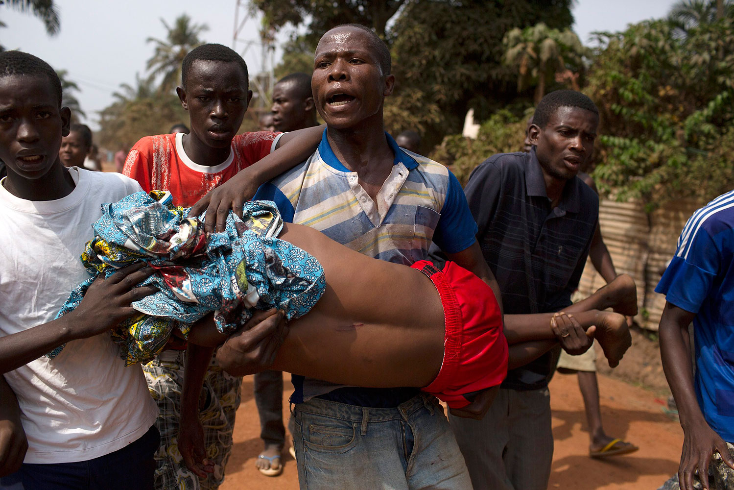 Men carry a boy, who died shortly after from a gunshot wound during a violent confrontation between Muslims and Christians, in Miskine district in the capital Bangui, Jan. 24, 2014.