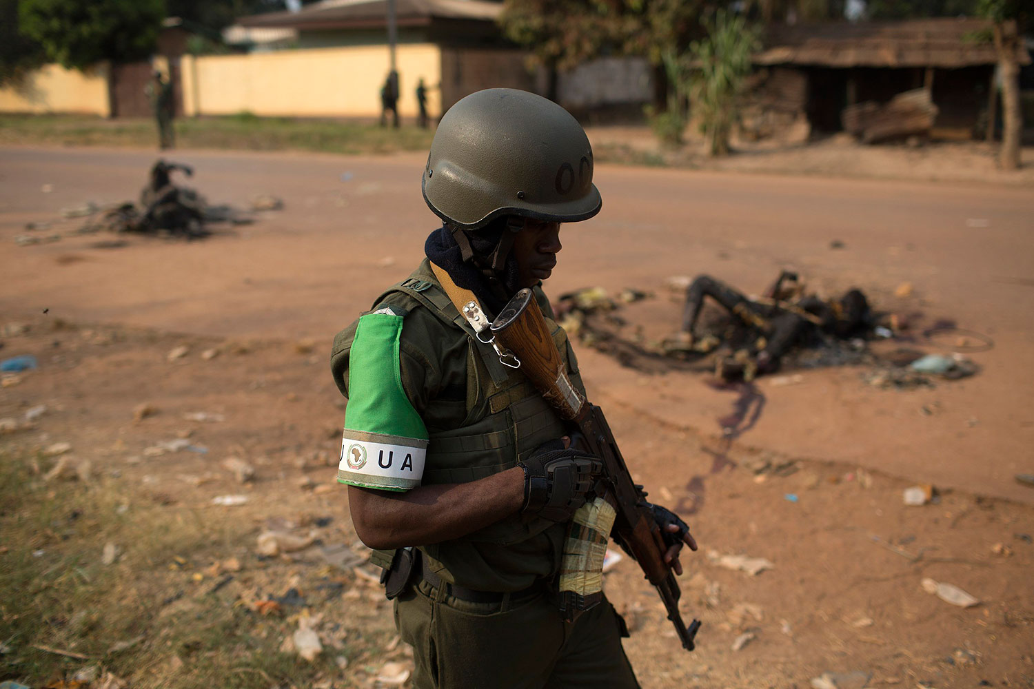 African Union peacekeeping soldier walks past burnt bodies of two Muslim men killed by a crowd in a street of the capital Bangui, Jan. 26, 2014.