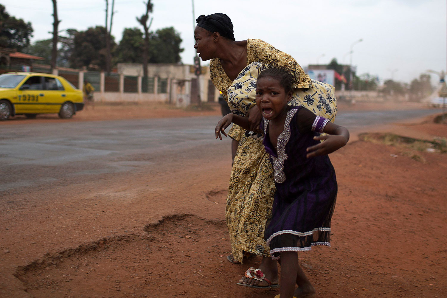 A mother holds her child while attempting to take cover as repeated gun shots are heard close to Miskine district during continuing sectarian violence in the capital Bangui, Jan. 28, 2014.