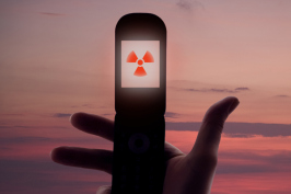 Hand holding a cellphone with radiation sign.