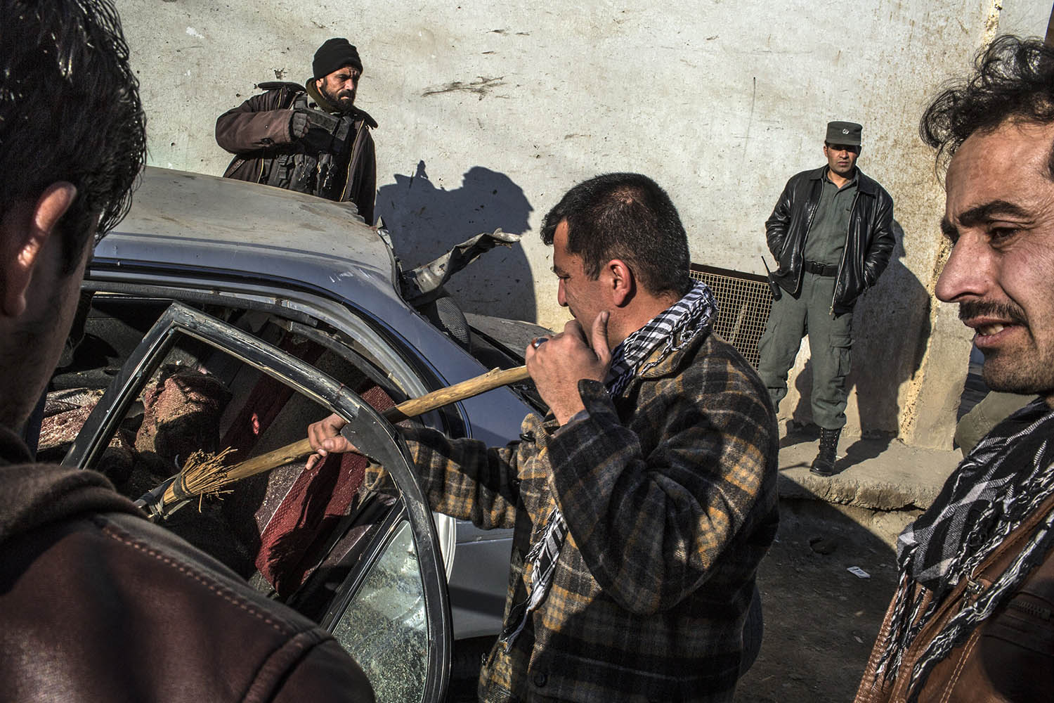Jan. 18, 2013. A man sweeps out his damaged car near the entrance of a restaurant that was attacked in Kabul, Afghanistan.