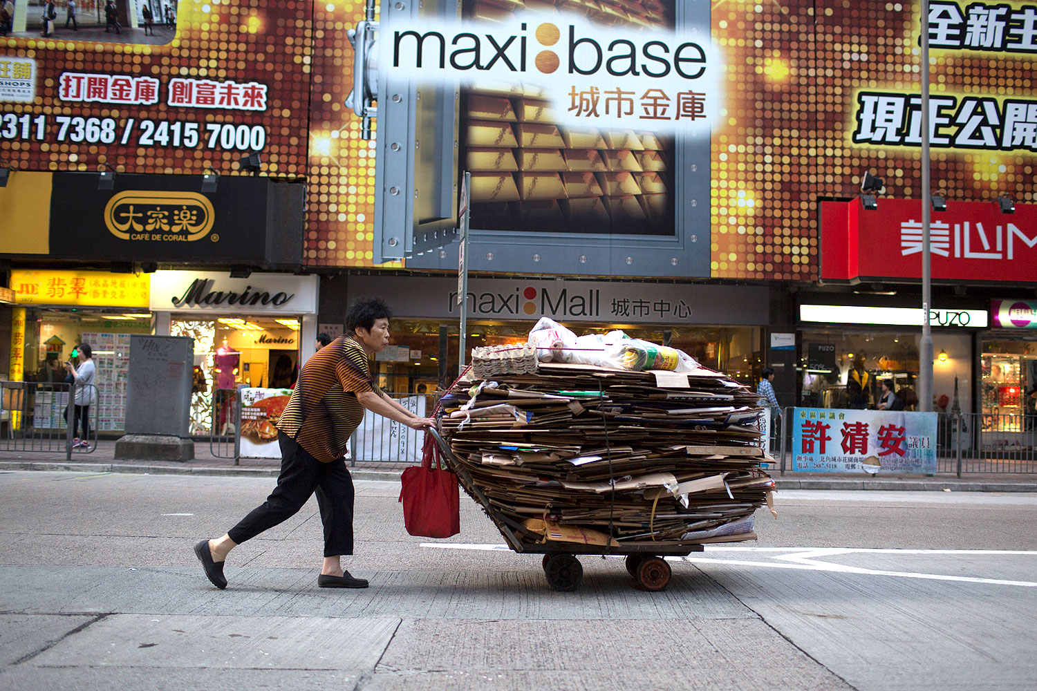 An elderly woman pushes a cart filled with cardboard for recycling in the North Point area of Hong Kong, China, on Oct. 18, 2013 (Brent Lewin / Bloomberg / Getty Images)