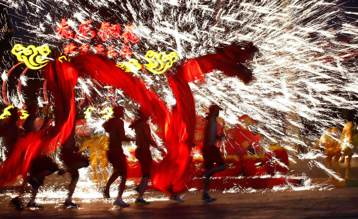 Dancers perform a fire dragon dance in the shower of molten iron spewing firework-like sparks during a folk art performance to celebrate the traditional Chinese Spring Festival on the first day of the Chinese Lunar New Year, which welcomes the Year of the Horse, at the Happy Valley amusement park in Beijing January 31, 2014. REUTERS/Kim Kyung-Hoon (CHINA - Tags: ANNIVERSARY SOCIETY TPX IMAGES OF THE DAY)