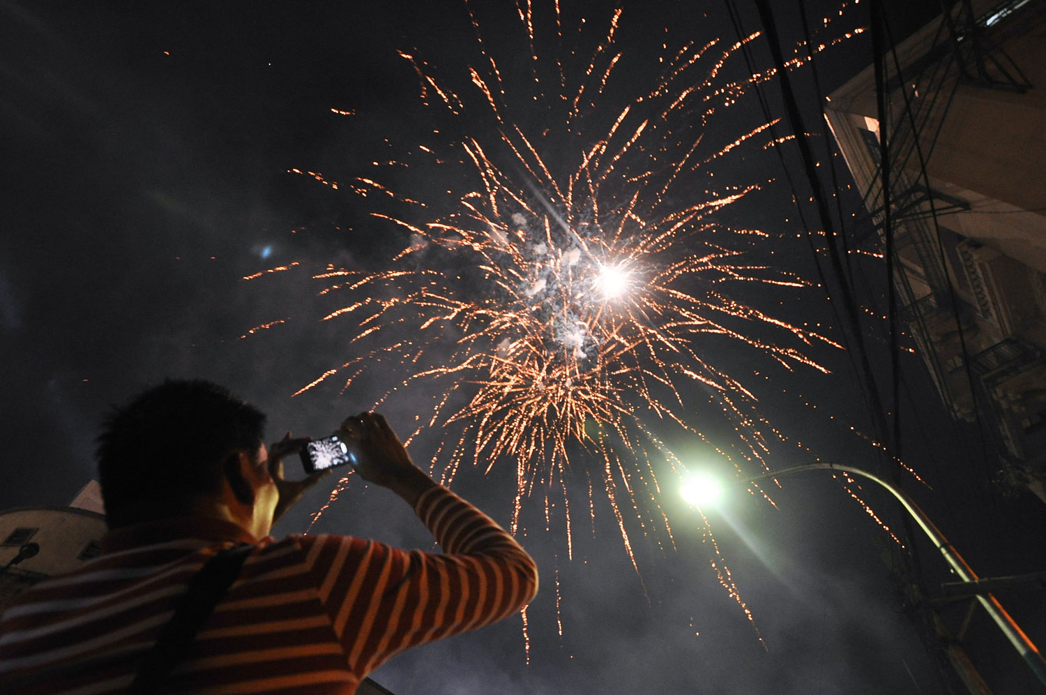 A man films the fireworks display using his phone in Chinatown, on the eve of Chinese New Year in Manila, Philippines, Jan. 30, 2014.