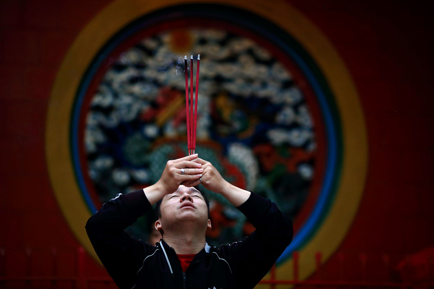 A man prays for good fortune while holding incense on the first day of the Chinese Lunar New Year at Petak Sembilan Temple, in Jakarta, Jan. 31, 2014.