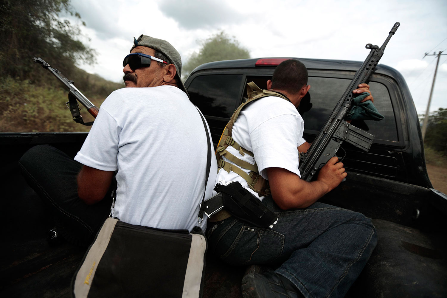 Vigilantes ride on the back of a pick-up truck while driving in a convoy to Poturo, Michoacan, Dec. 29, 2013.