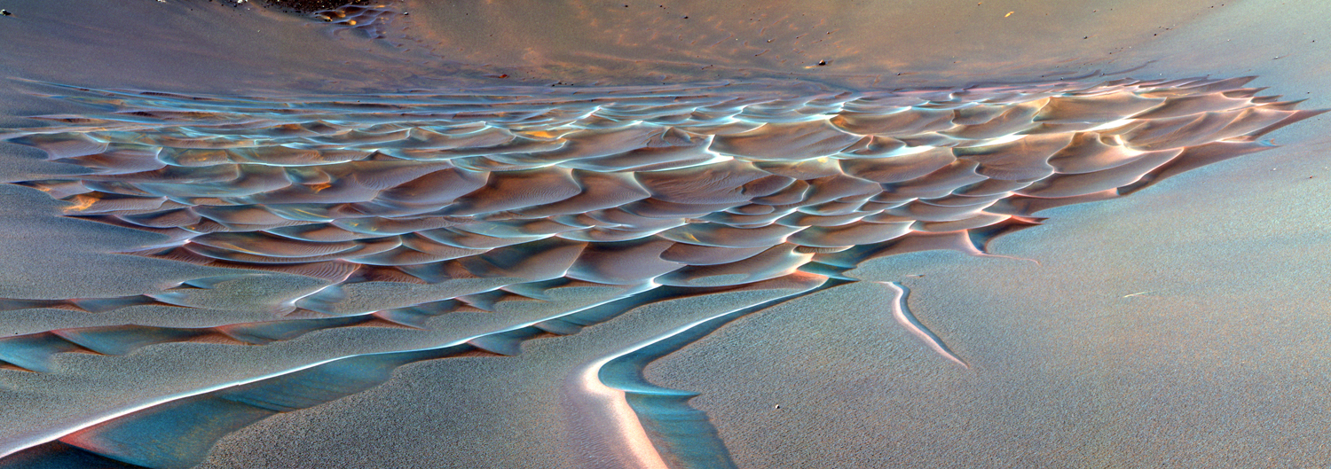 A false-color image of Endurance Crater. In this image, tendrils of sand less than 3.3 ft (1 m) high extend from the main dune field toward the rover. Dunes are a common feature across the surface of Mars. Before the rover headed down to the dunes, mission managers first established whether the slippery slope that led to them was firm enough to ensure a successful drive back out of the crater. Otherwise, the dune field would become a sand trap.