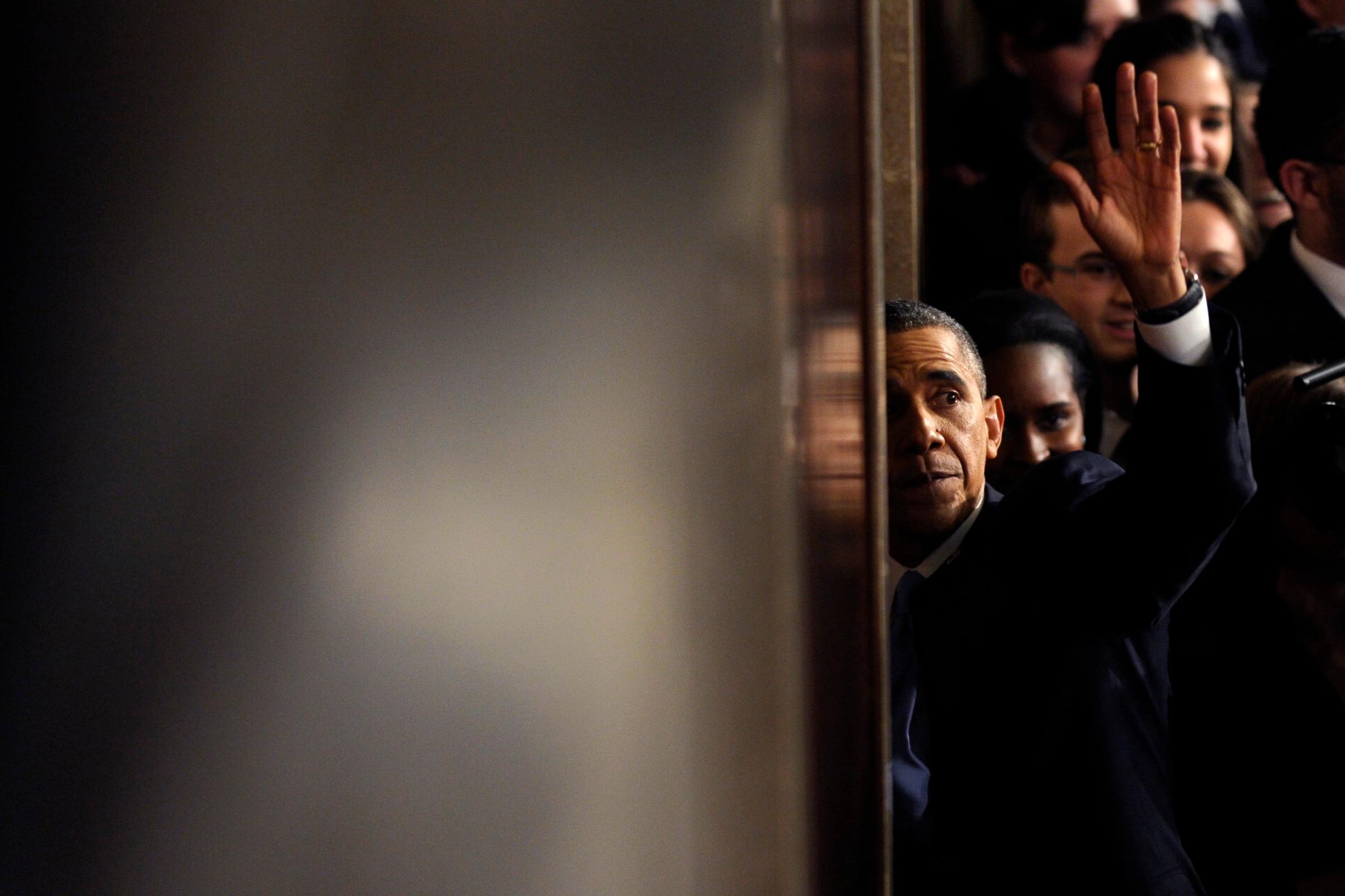 President Barack Obama waves as he walks through a door to leave the House chamber after giving his State of the Union address.