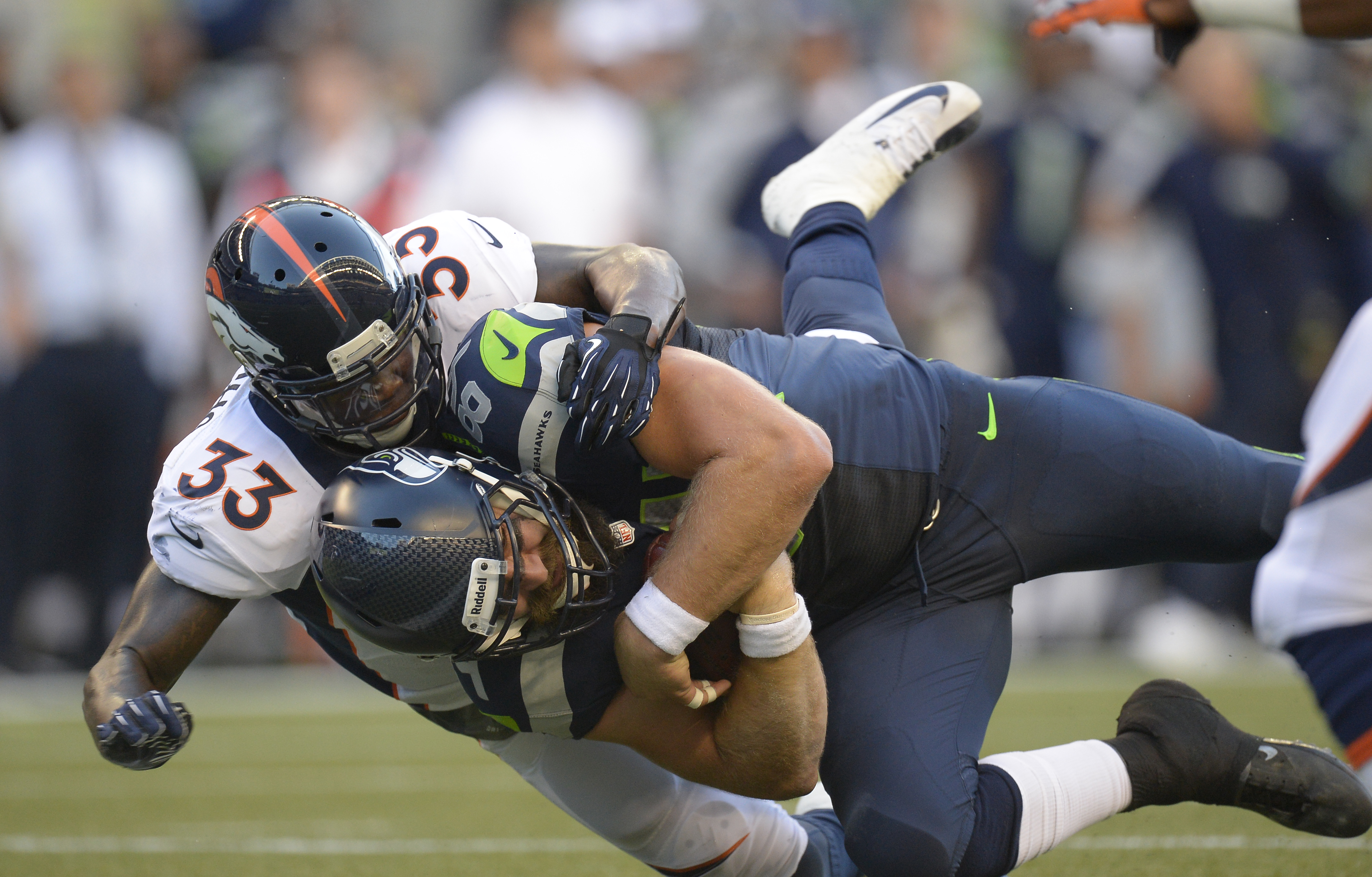 Seattle Seahawks tight end Sean McGrath (84) gets wrapped up by Denver Broncos safety Duke Ihenacho (33) after a gain during the first quarter, on Aug. 17, 2013 at Century Link Field in Seattle. (John Leyba / Denver Post / Getty Images)