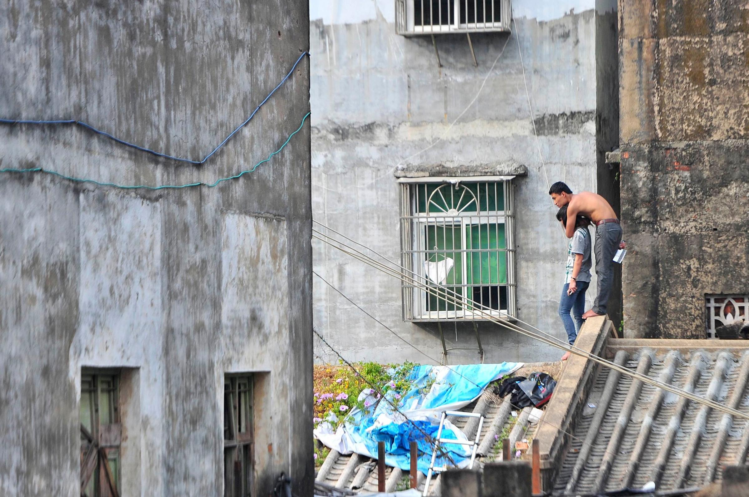 A topless man holds his girlfriend hostage with a knife atop a residential building in Sanya, Hainan province, Jan. 20, 2014. According to local media, the man, surnamed Lin, held his girlfriend hostage to threaten both families into allowing their marriage. Lin stood off with police on the roof for several hours and was arrested soon after he got down the building.