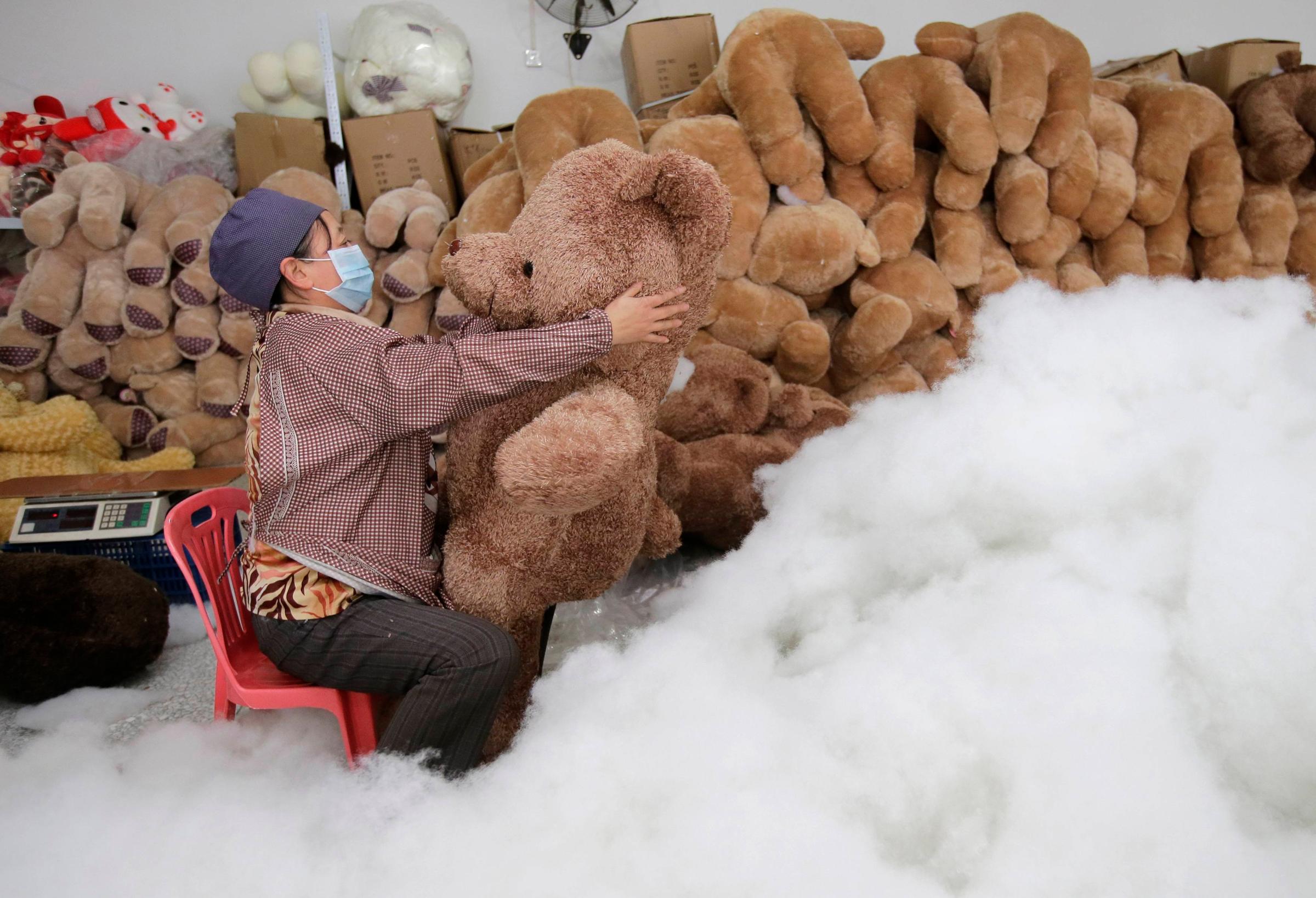 A worker stuffs a toy bear with cotton at a toy factory in Wuhan, Hubei province, Jan. 15, 2014.