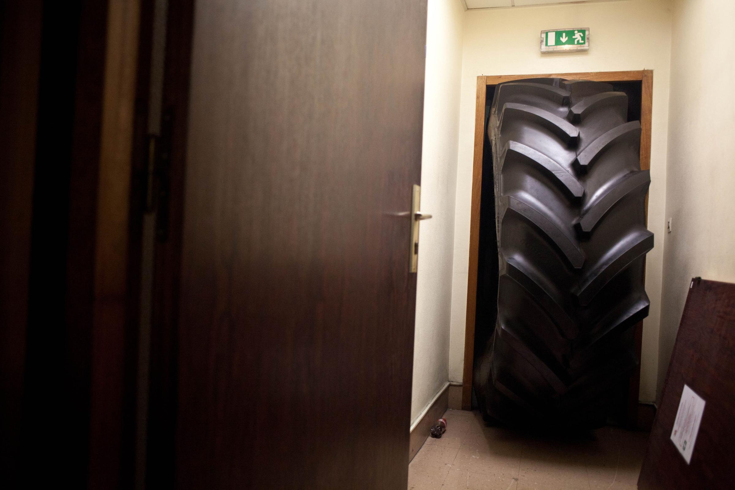 A huge tire blocks the door where Goodyear Factory production workers, Michel Dheilly and Bernard Glesser, were being detained by workers, Jan. 6, 2014, in Amiens, France.
