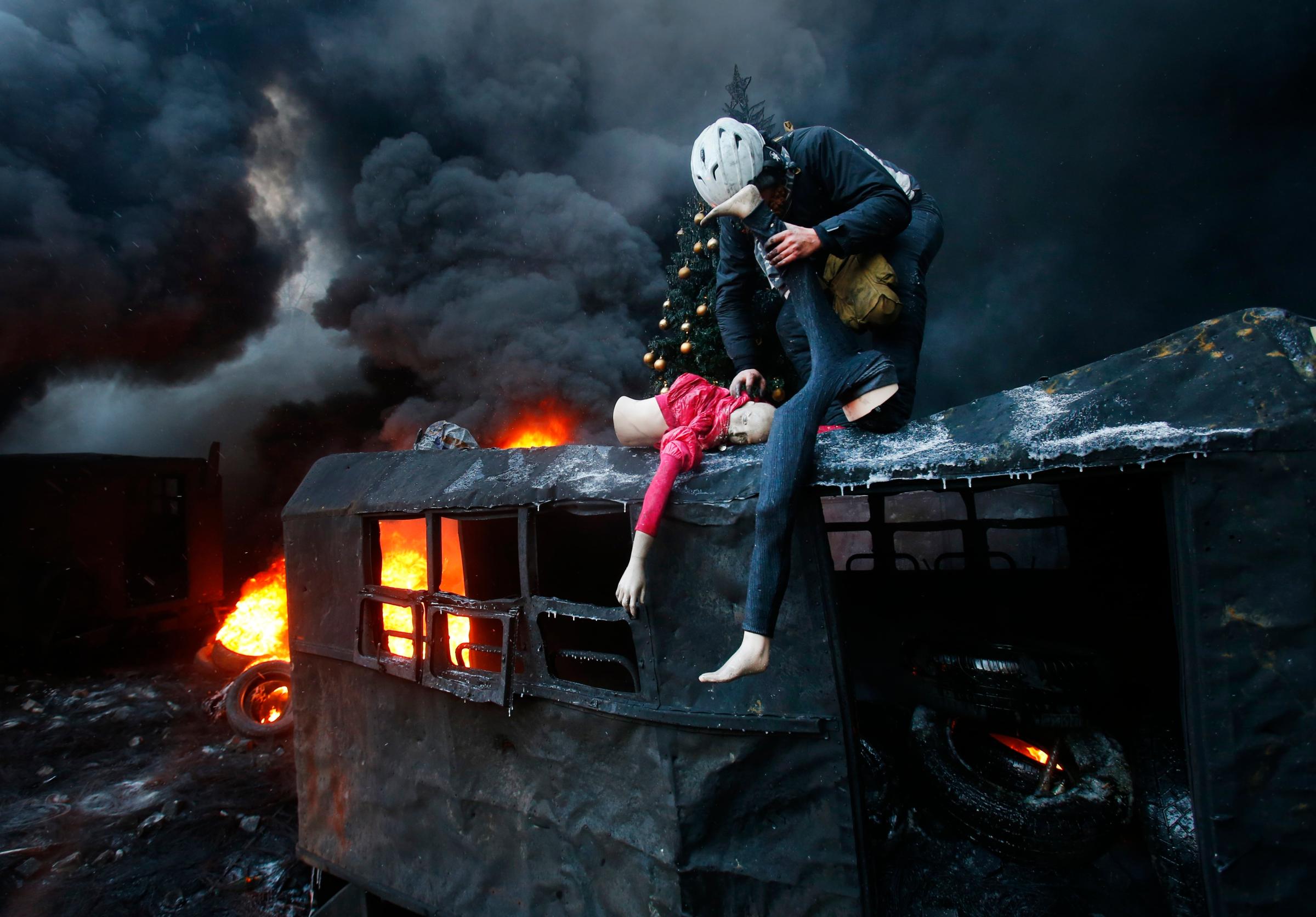 A protester breaks up a mannequin on the roof of the burned truck during clashes with police in central Kiev, Ukraine, Thursday Jan. 23, 2014.